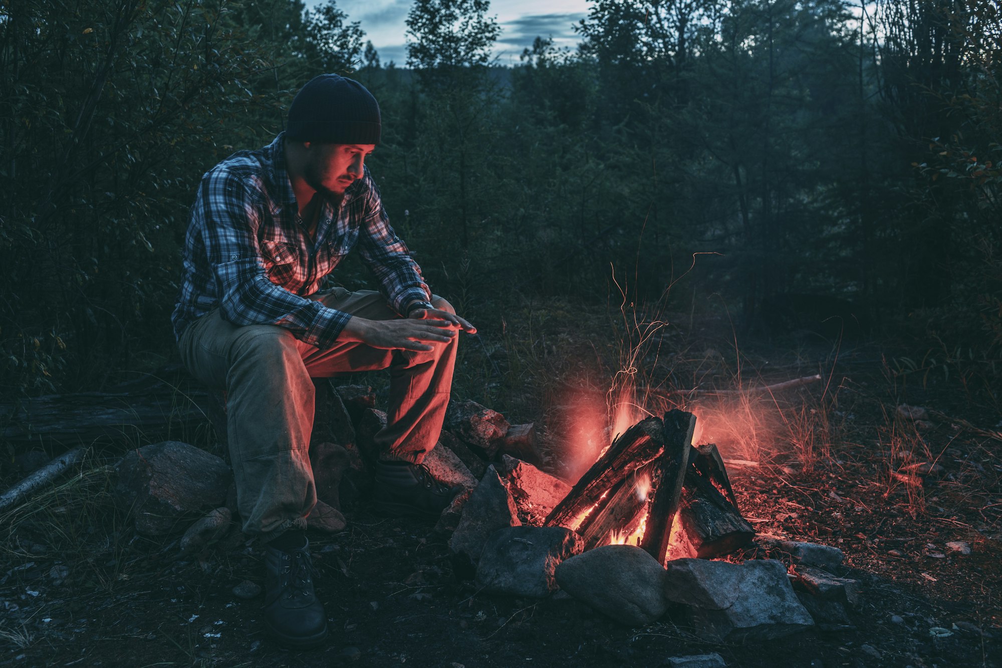 Man sitting at campfire in rural landscape